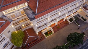 Un hotel de varios pisos con patio, balcones y un jardín central.