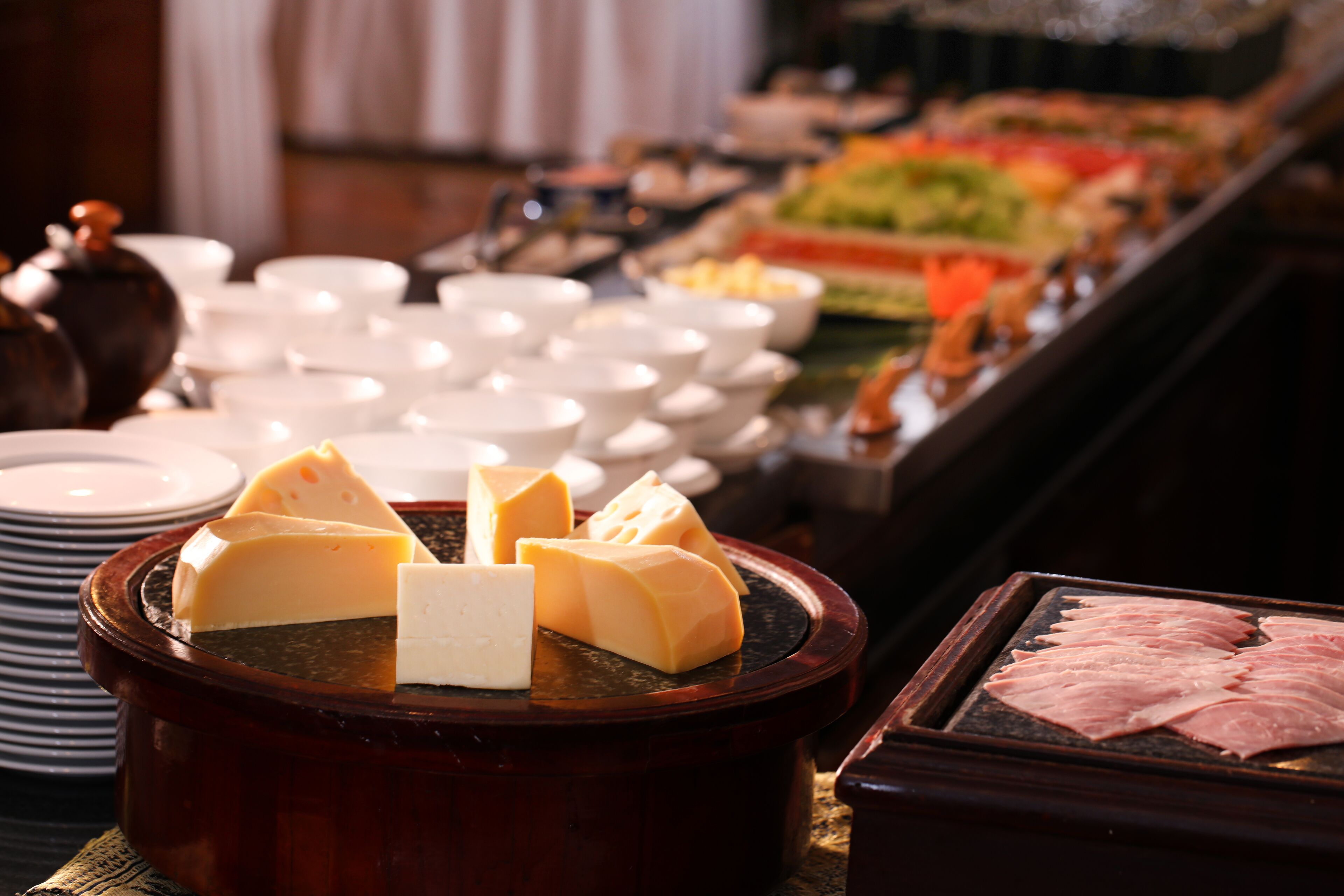 Un bufé con diversos alimentos, como queso y carne, y múltiples tazones y platos.