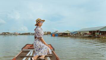 A person sitting on a boat with a view of a waterway and buildings in the background.