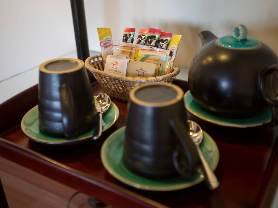 Un juego de té con dos tazas y una tetera sobre una bandeja, acompañado de una cesta de bolsitas de té.