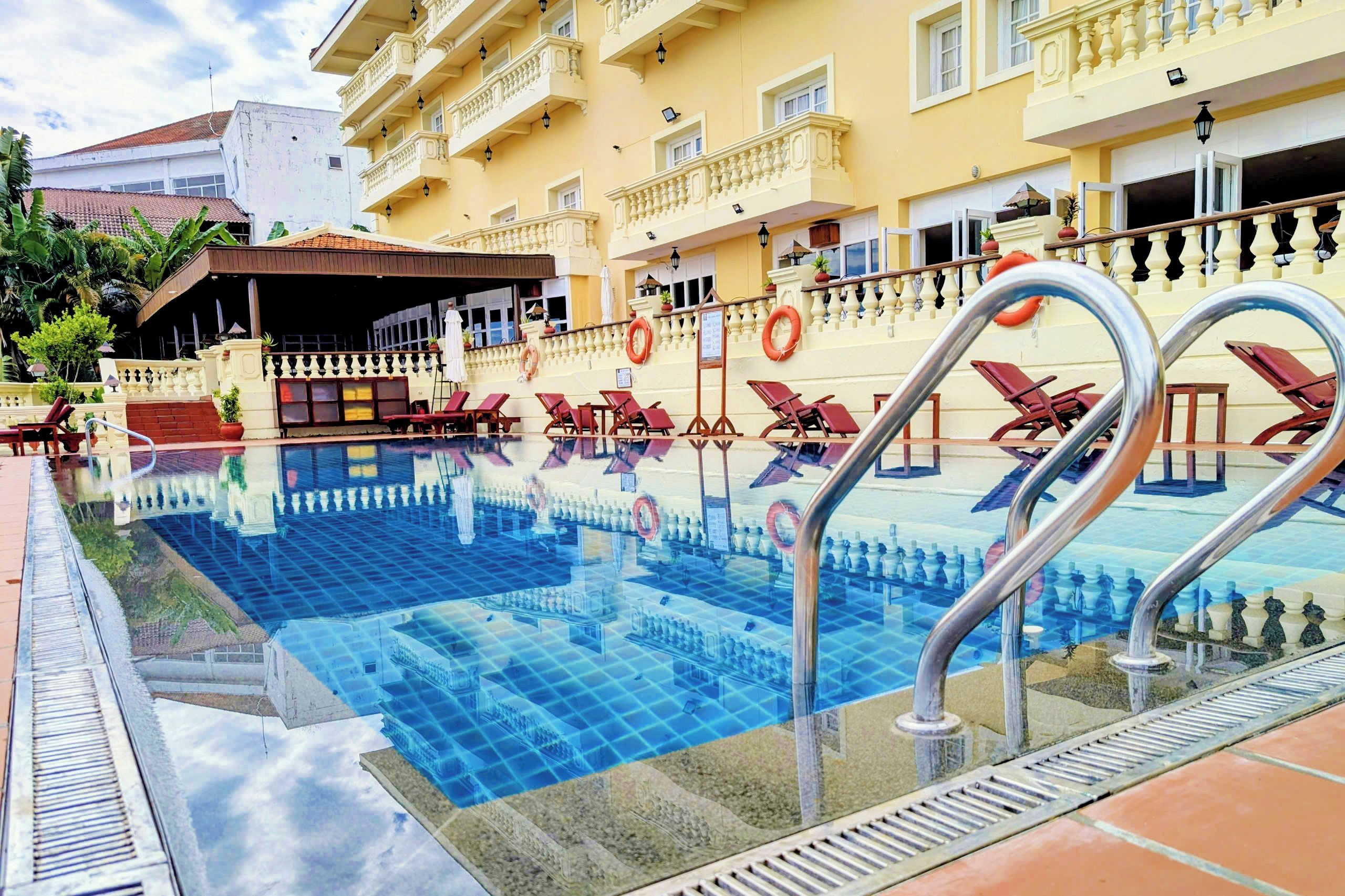 Une piscine d’hôtel avec des chaises longues et une bouée de sauvetage.