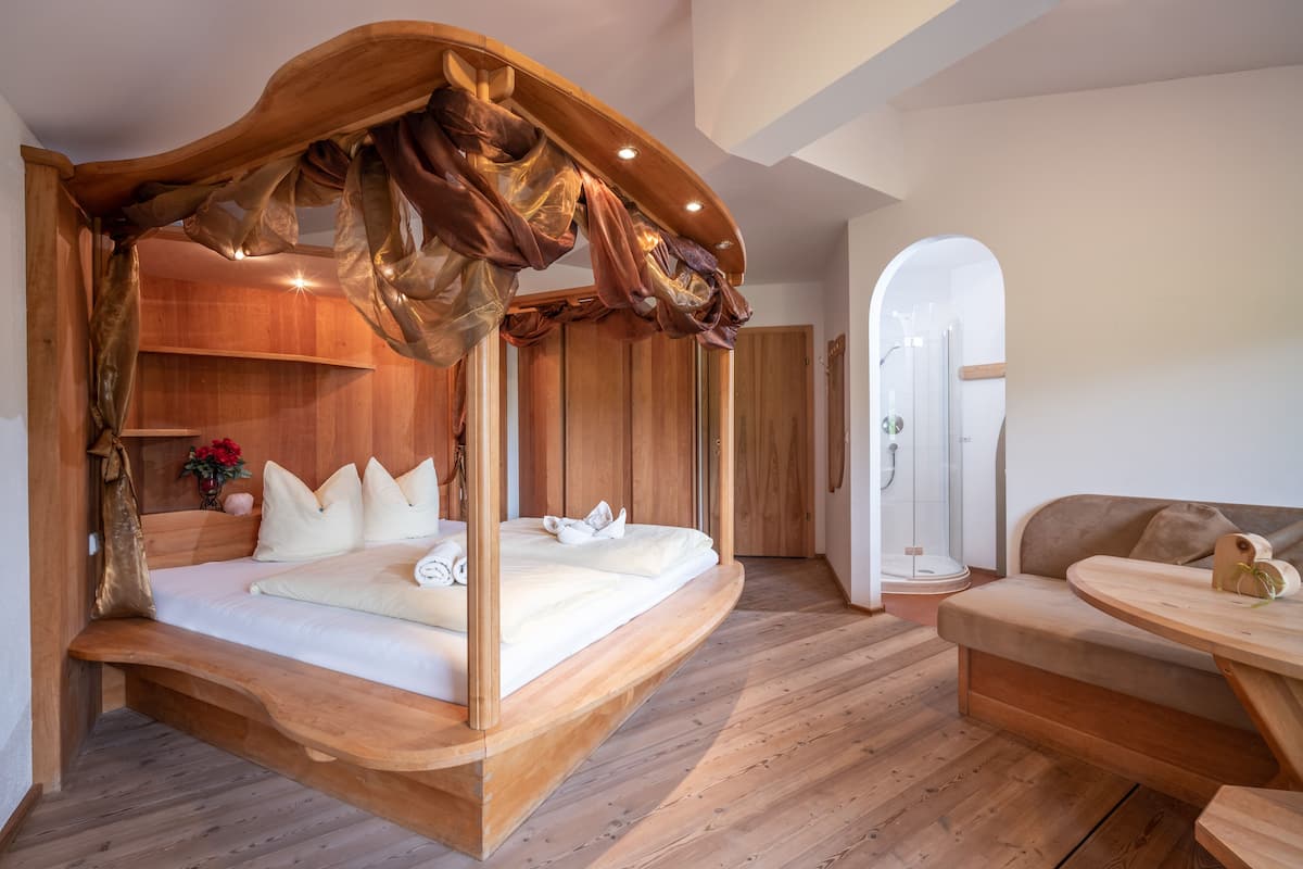 Ein Schlafzimmer mit einem hölzernen Baldachinbett, einer Holzbank und einem runden Holztisch.