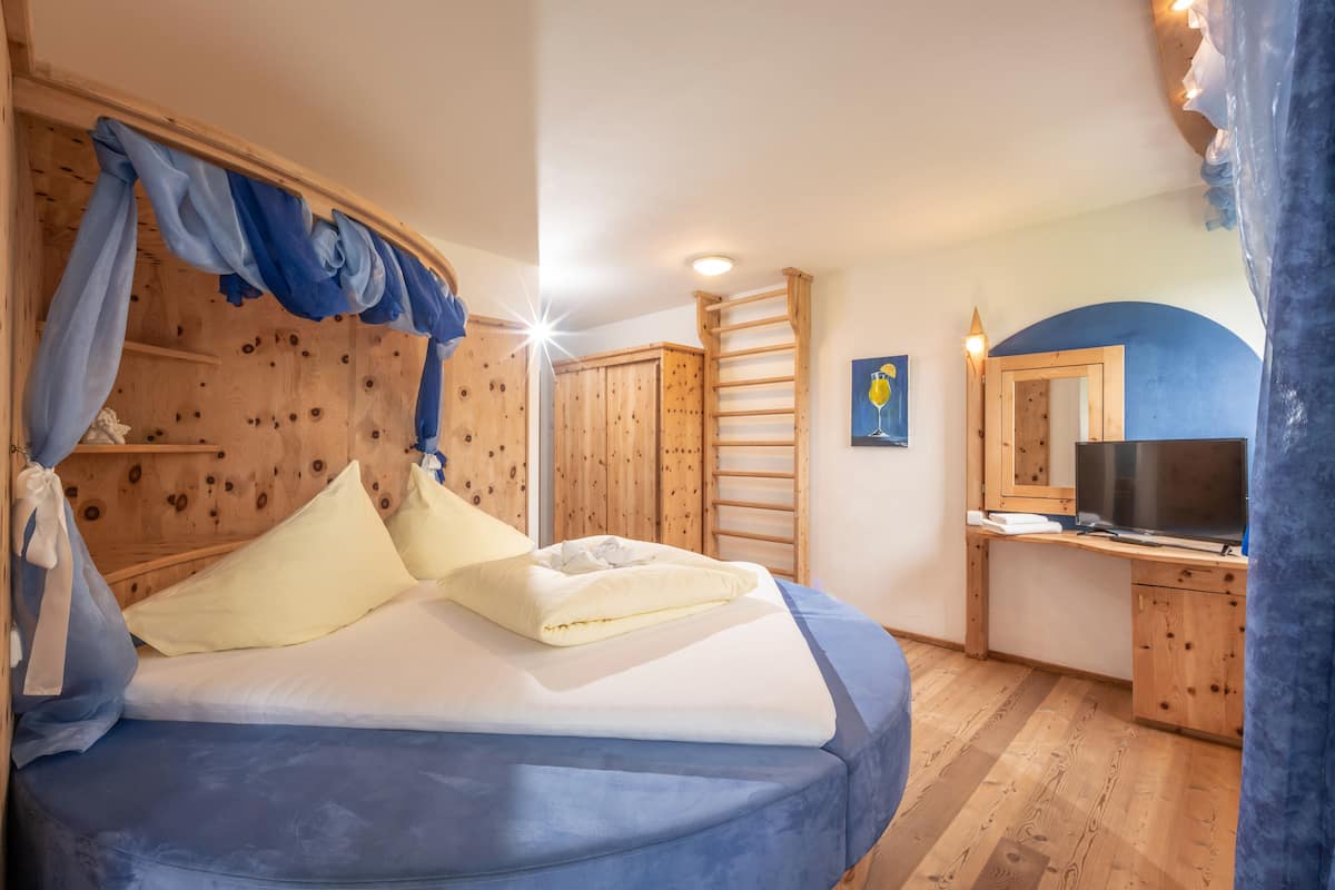 Ein Schlafzimmer mit einem Bett, einem Holzkopfstück, einem Schreibtisch mit Spiegel und einem Fernseher.