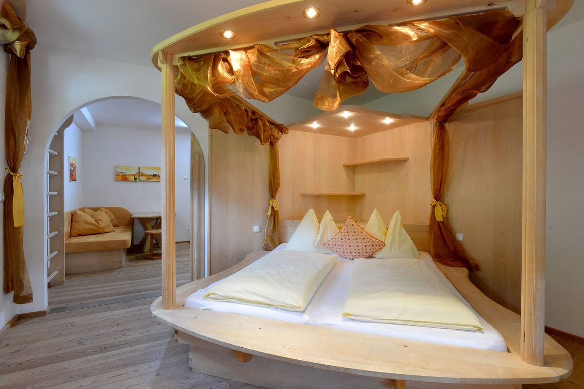 Ein Zimmer mit einem großen Bett, einer Couch und Holzboden.