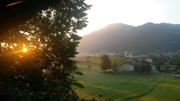 Et landligt landskab med en kirke, huse og et træ i forgrunden.