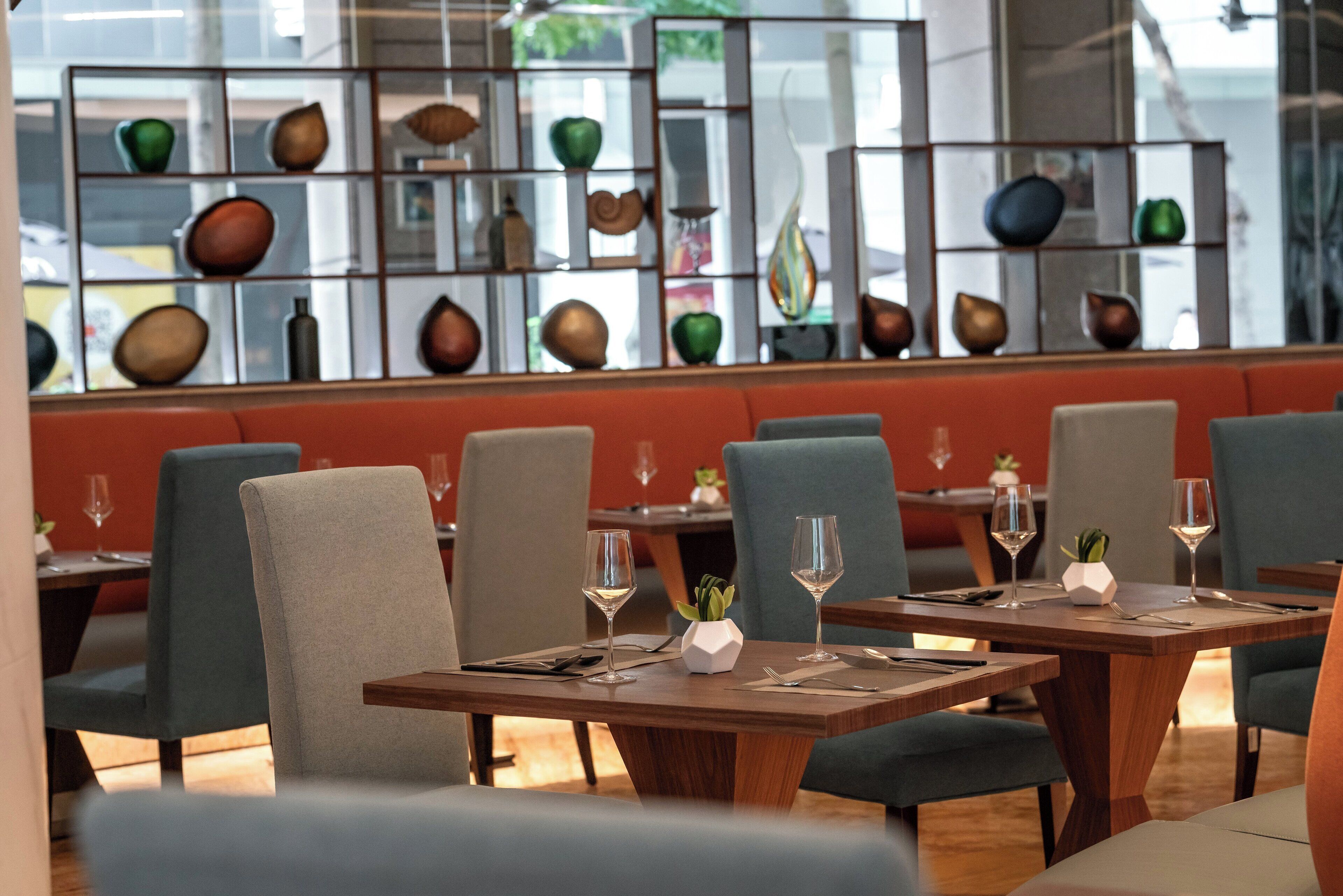 A restaurant interior with multiple tables, chairs, and a decorative wall with various objects.