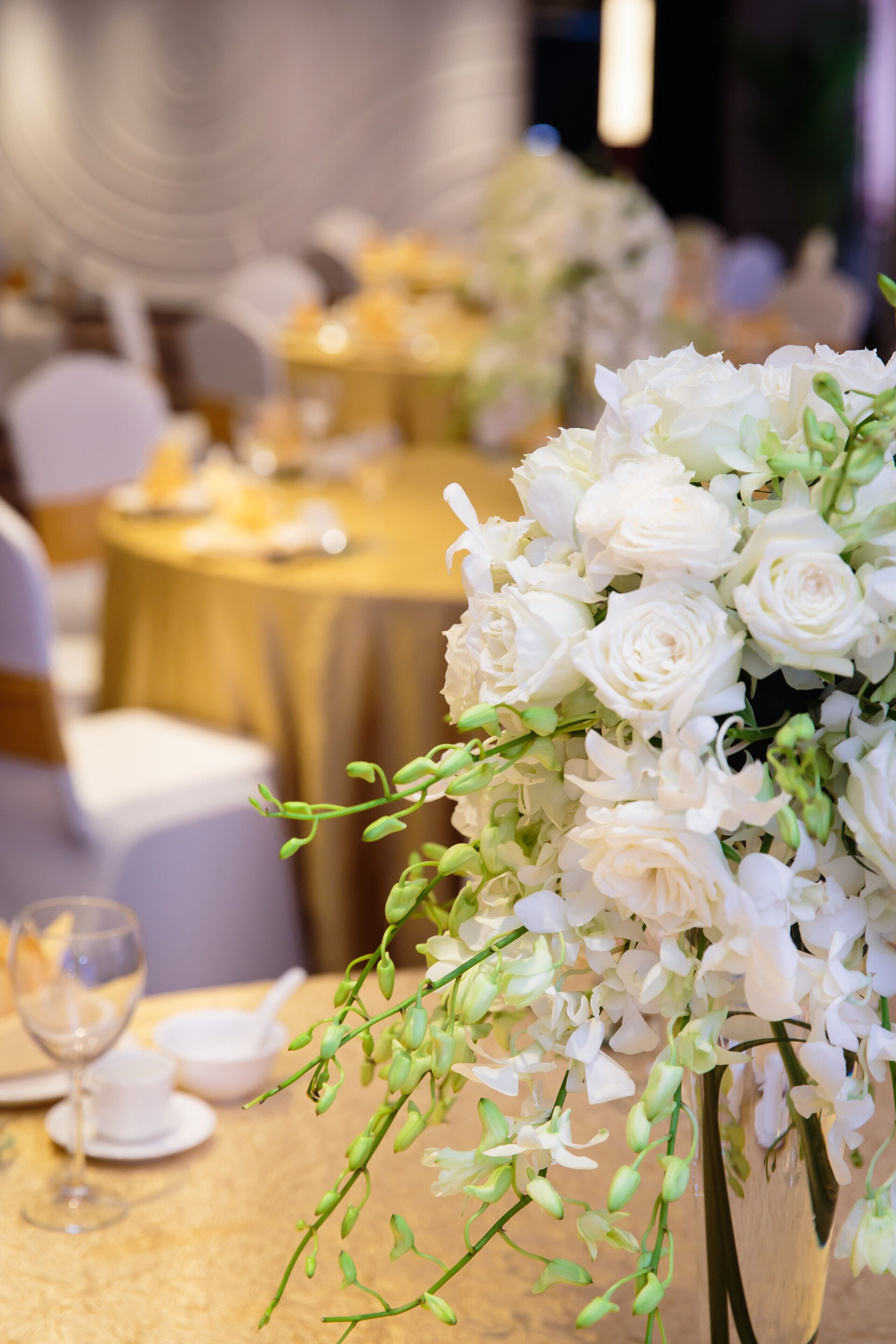 A table with a white floral arrangement, a glass, and a bowl.
