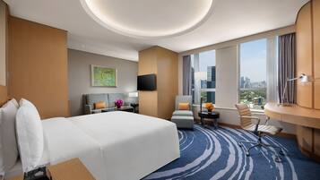 Une chambre d’hôtel avec un grand lit, un bureau, une chaise, une télévision et une vue sur la ville.