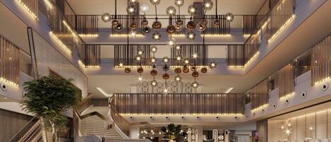 Un vestíbulo espacioso con una imponente escalera, candelabros modernos y un mostrador de recepción.
