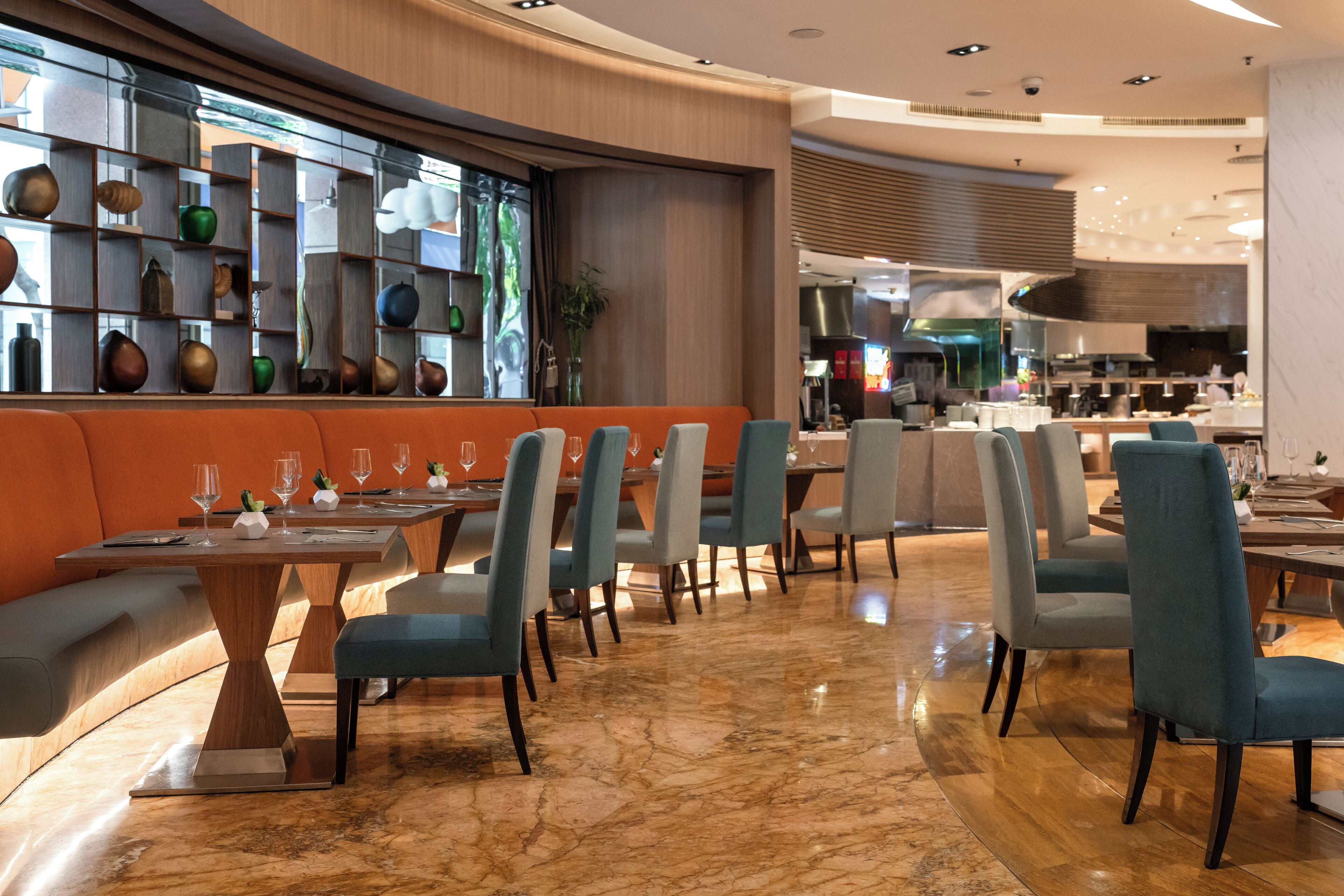 A modern restaurant with a curved seating area, marble flooring, and a variety of decorative items on shelves.