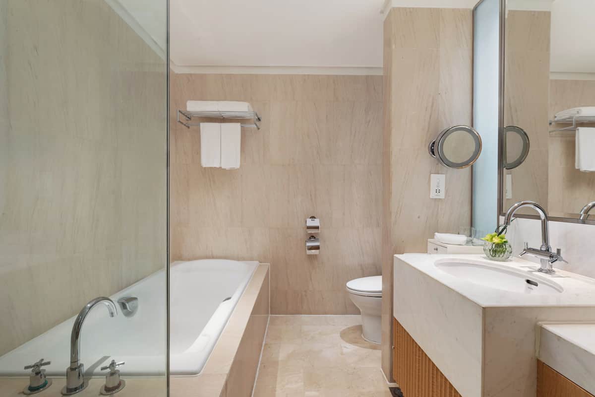 Ein modernes Badezimmer mit Duschkabine aus Glas, einer Badewanne, einer Toilette und einem Waschbecken mit Spiegel.