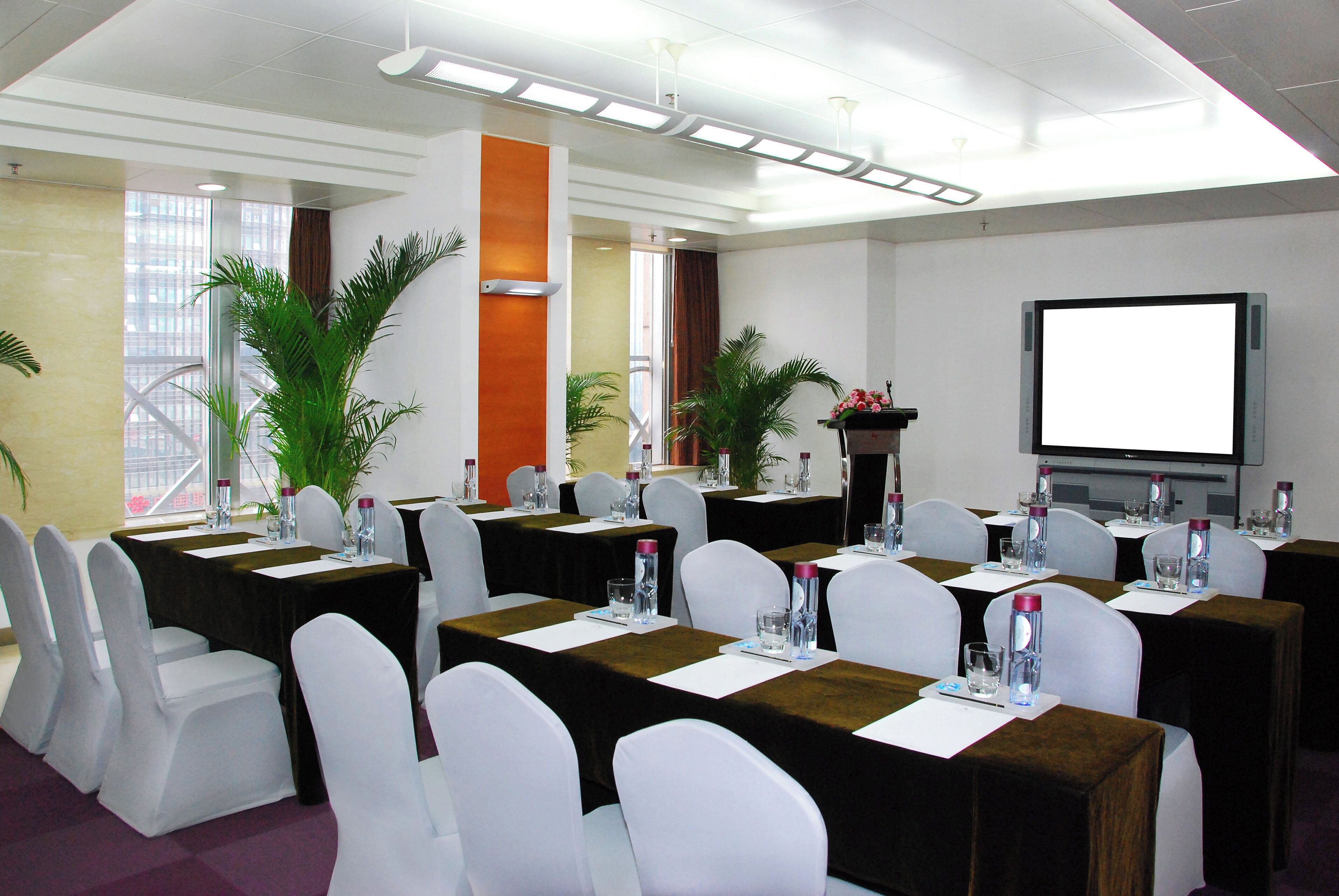 A conference room with tables set for a meeting, equipped with water bottles and nameplates.