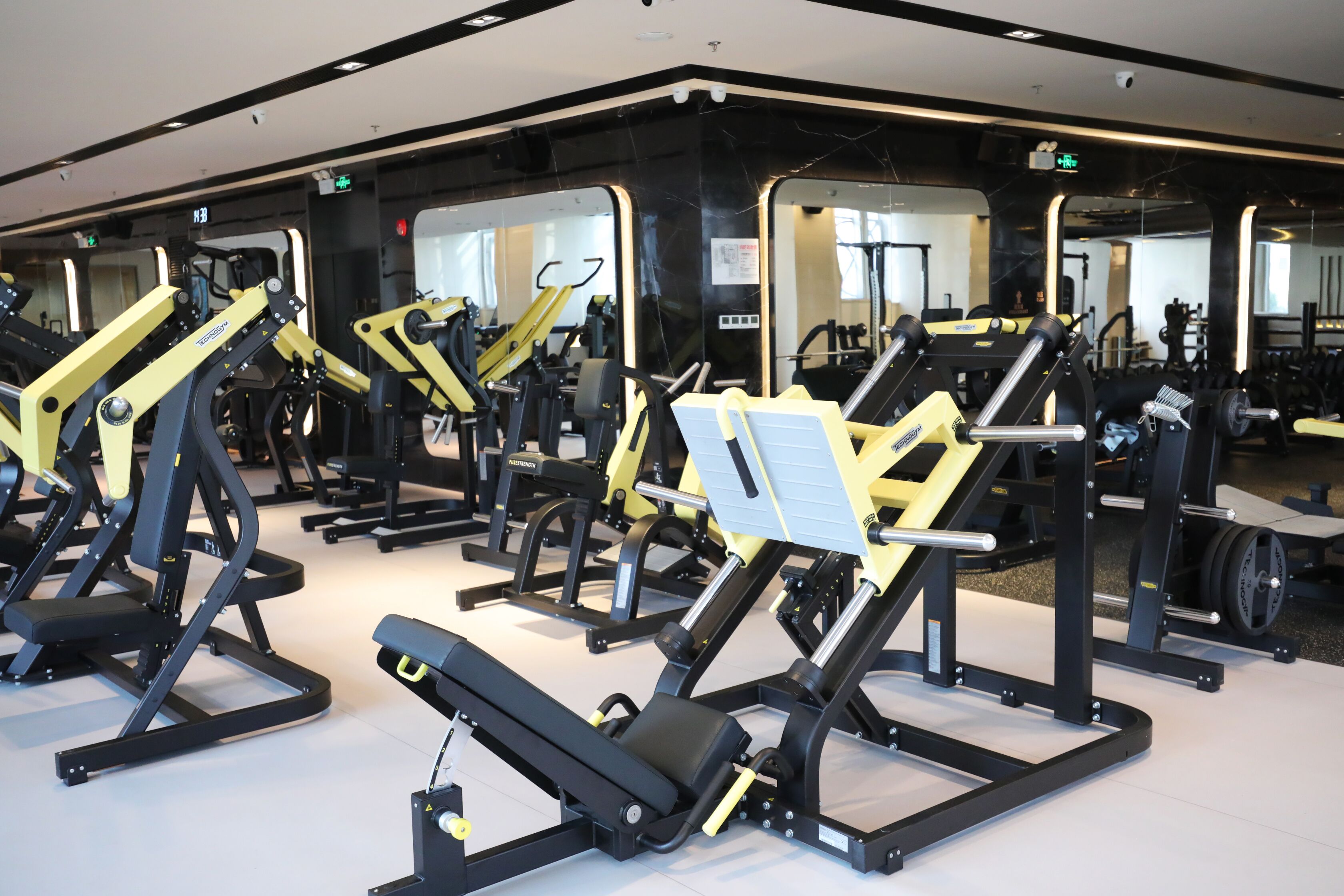 Une salle de sport équipée de nombreux appareils d’exercice, de miroirs et dotée d’un design moderne et épuré.
