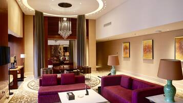 A hotel lobby with a modern chandelier, plush red sofas, a coffee table, and artwork on the walls.