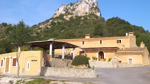 A building with a stone facade, a courtyard, and a mountain in the background. - Agroturisme Es Picot (Manacor)