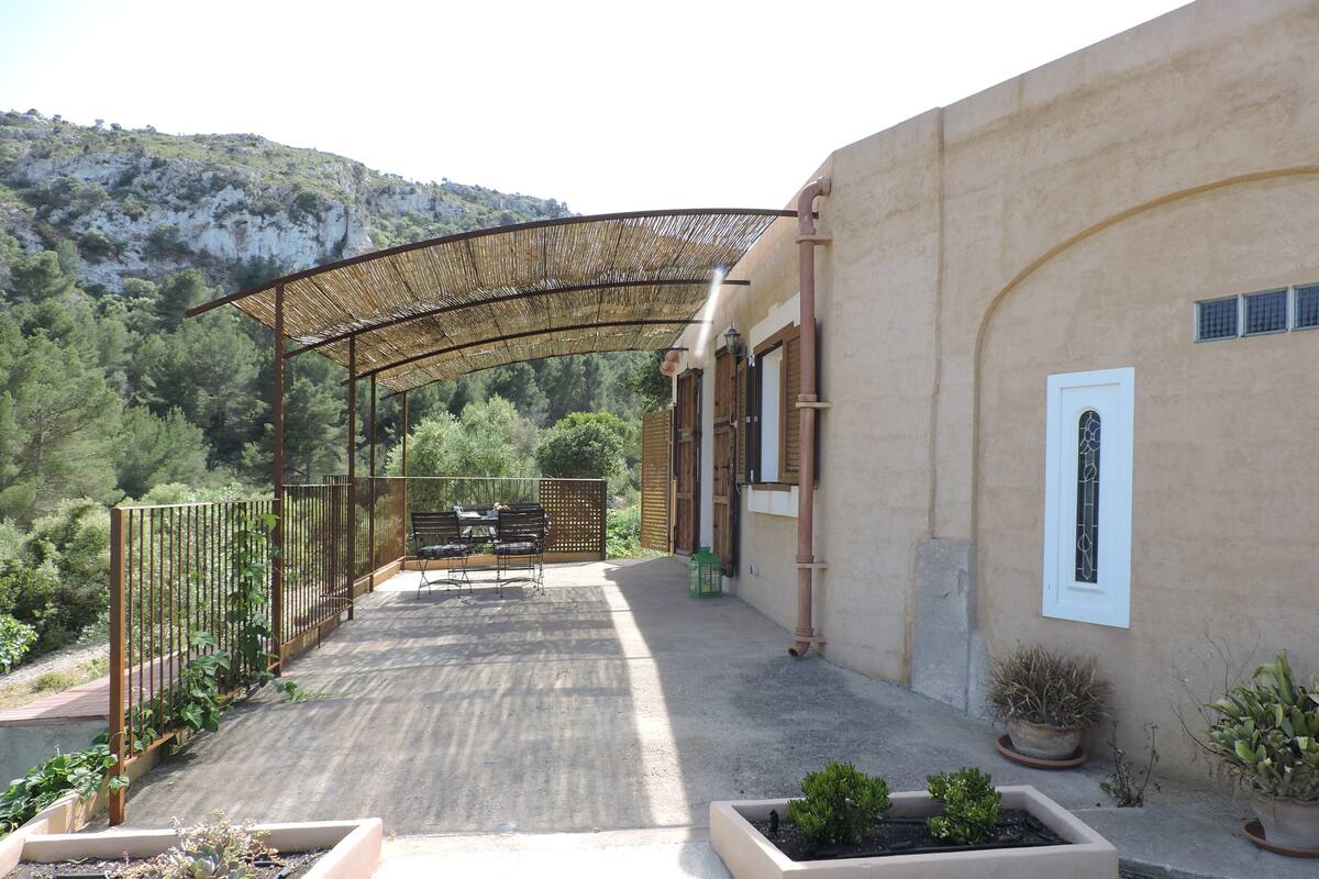 An outdoor patio with a pergola, seating area, and potted plants.