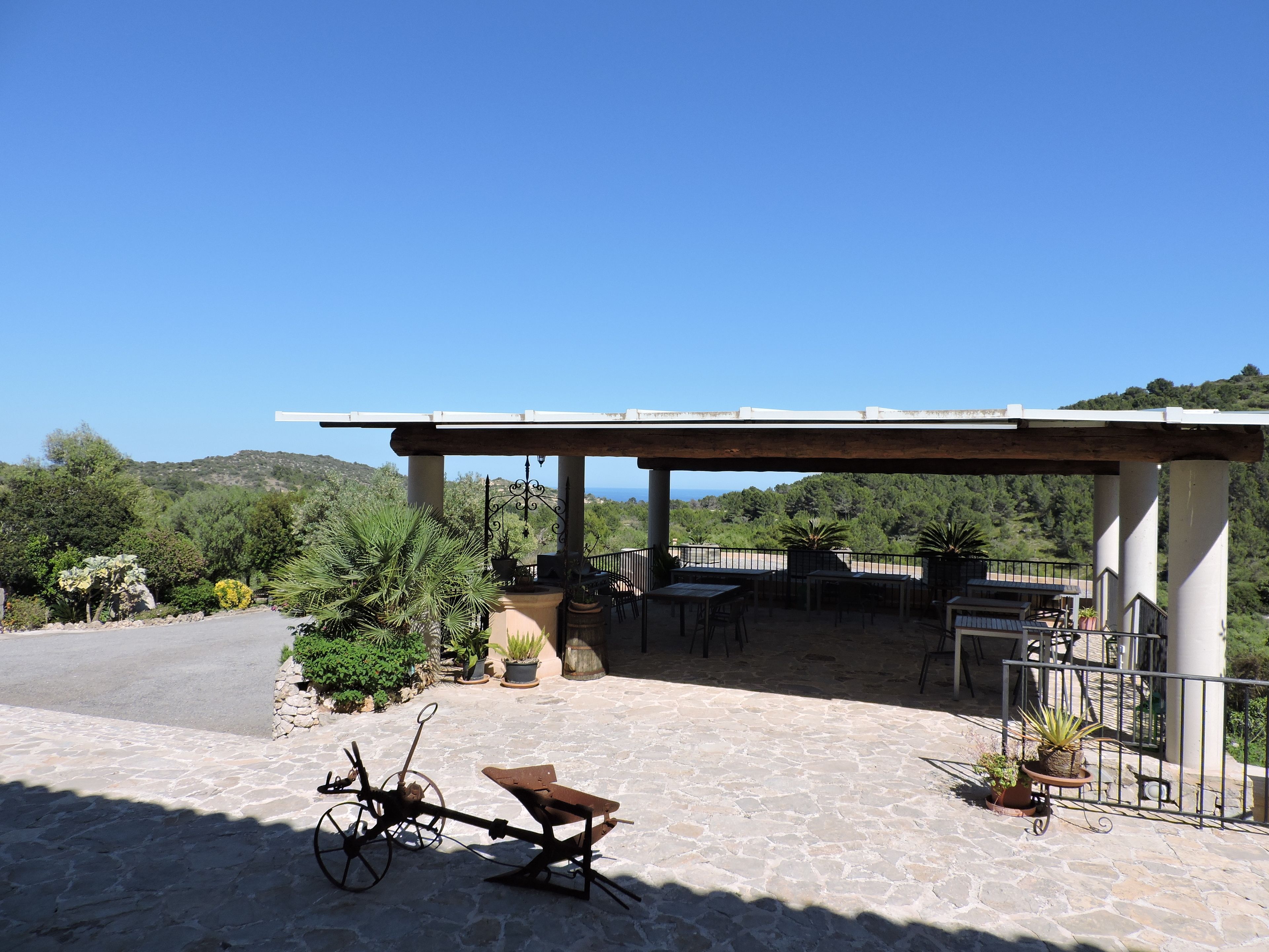A covered outdoor area with stone flooring, a bicycle, and potted plants.