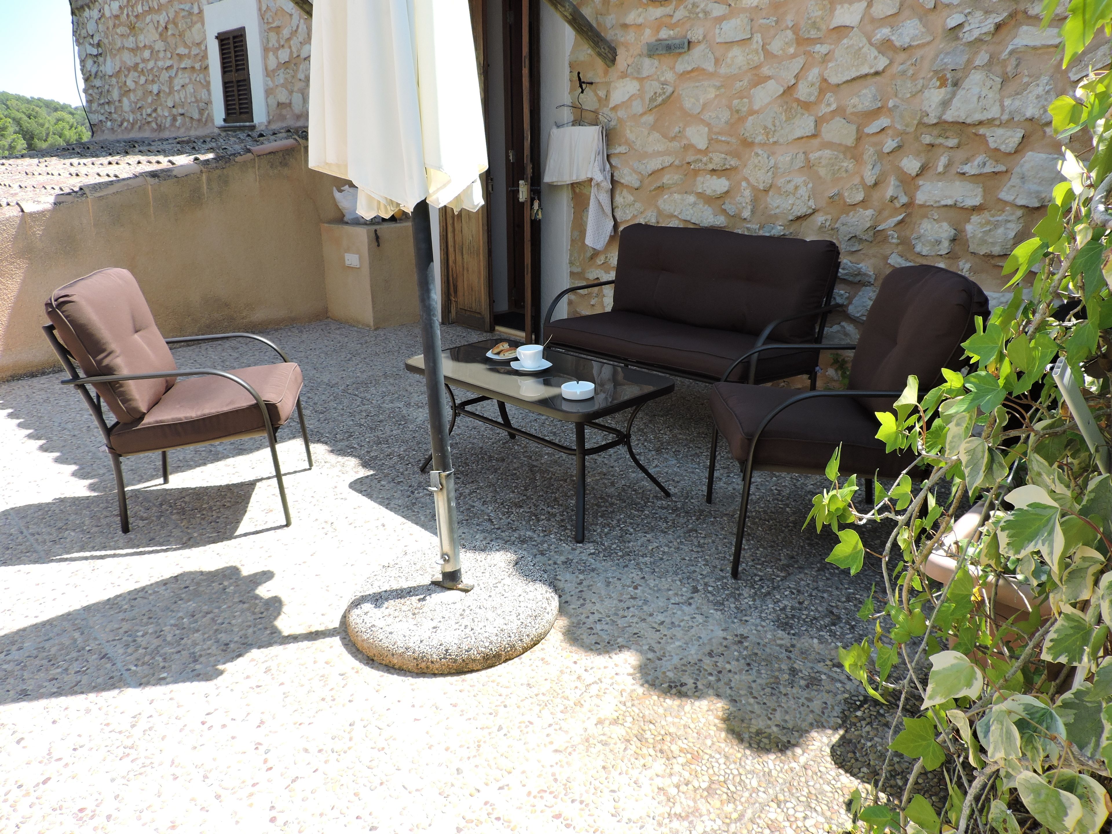 Un espace extérieur aménagé avec une table, deux chaises et une lampe.