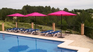 A poolside area with lounge chairs and pink umbrellas. - Agroturisme Es Picot (Manacor)