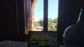 A laptop on a table with a view of a garden through a window. - Agroturisme Es Picot (Manacor)