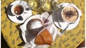 A table with a yellow tablecloth, a cup of coffee, two glasses of white wine, a pastry, and a croissant. - Soggiorno Paradiso due (Naples)