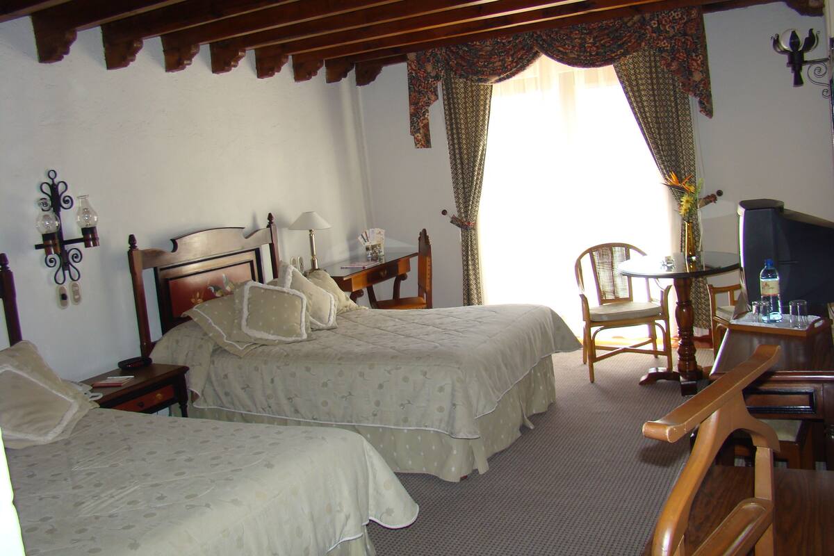 A room with two beds, a desk, a chair, and a television.