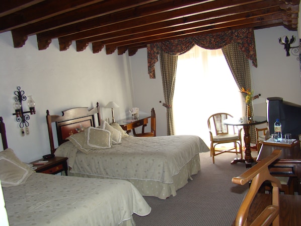 Una habitación con dos camas, un escritorio, una silla y una televisión.