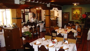 Un restaurante con vigas de madera, manteles blancos y un candelabro.