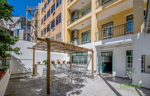 A courtyard with outdoor seating, a pergola, and a building with multiple balconies. - Hotel Italia (Lisbon)