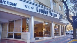 Exterior de un hotel con un letrero que dice 'Condor Suites' y una entrada visible con puertas de vidrio.
