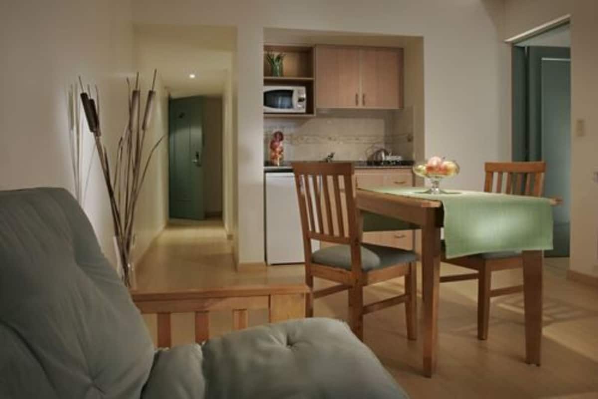 A compact living space with a dining area, kitchenette, and a visible door leading to another room.