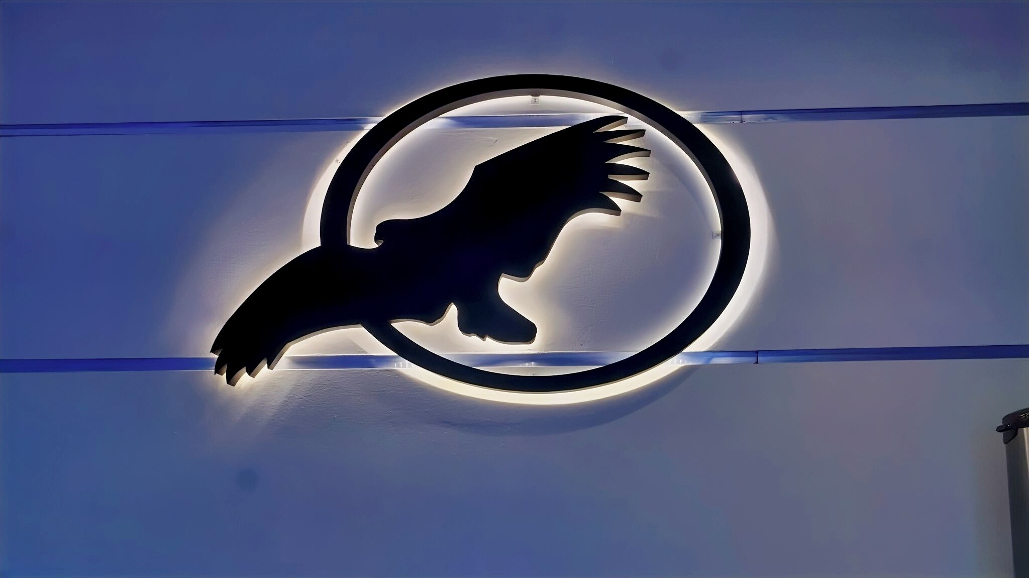 Logotipo circular con la silueta de un ave en una pared.
