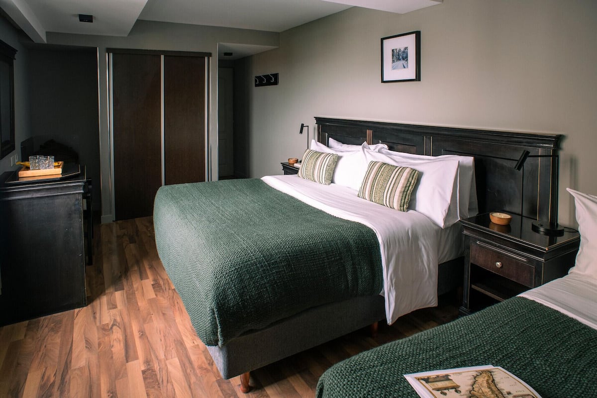 A hotel room with a large bed, a bedside table, a dresser, and a framed picture on the wall.
