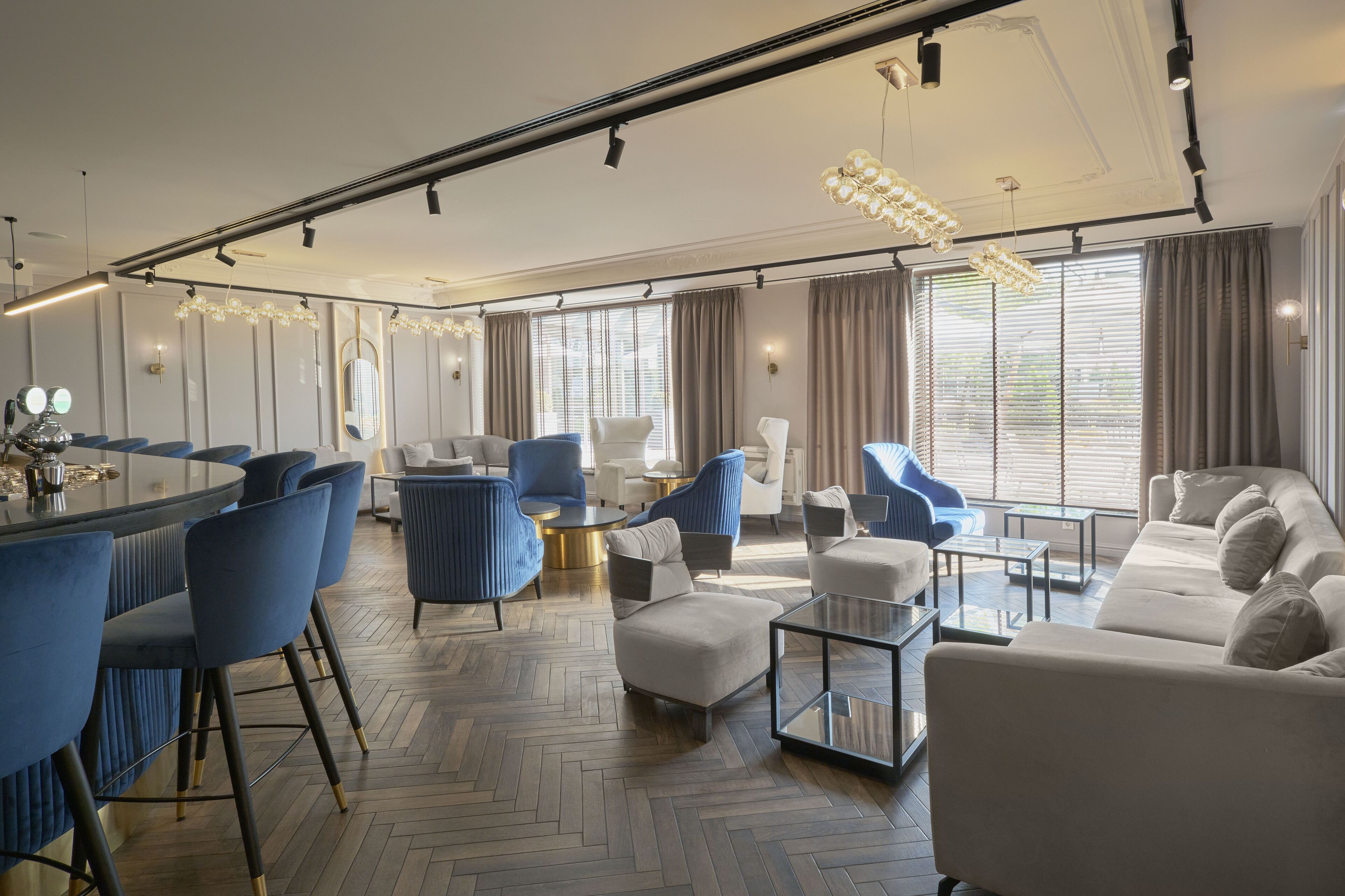 A modern hotel room with a dining area, seating, and a large window with curtains.