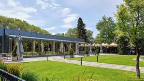 Un espace extérieur moderne, aménagé avec des murs en verre, une pelouse bien entretenue et divers types de mobilier.