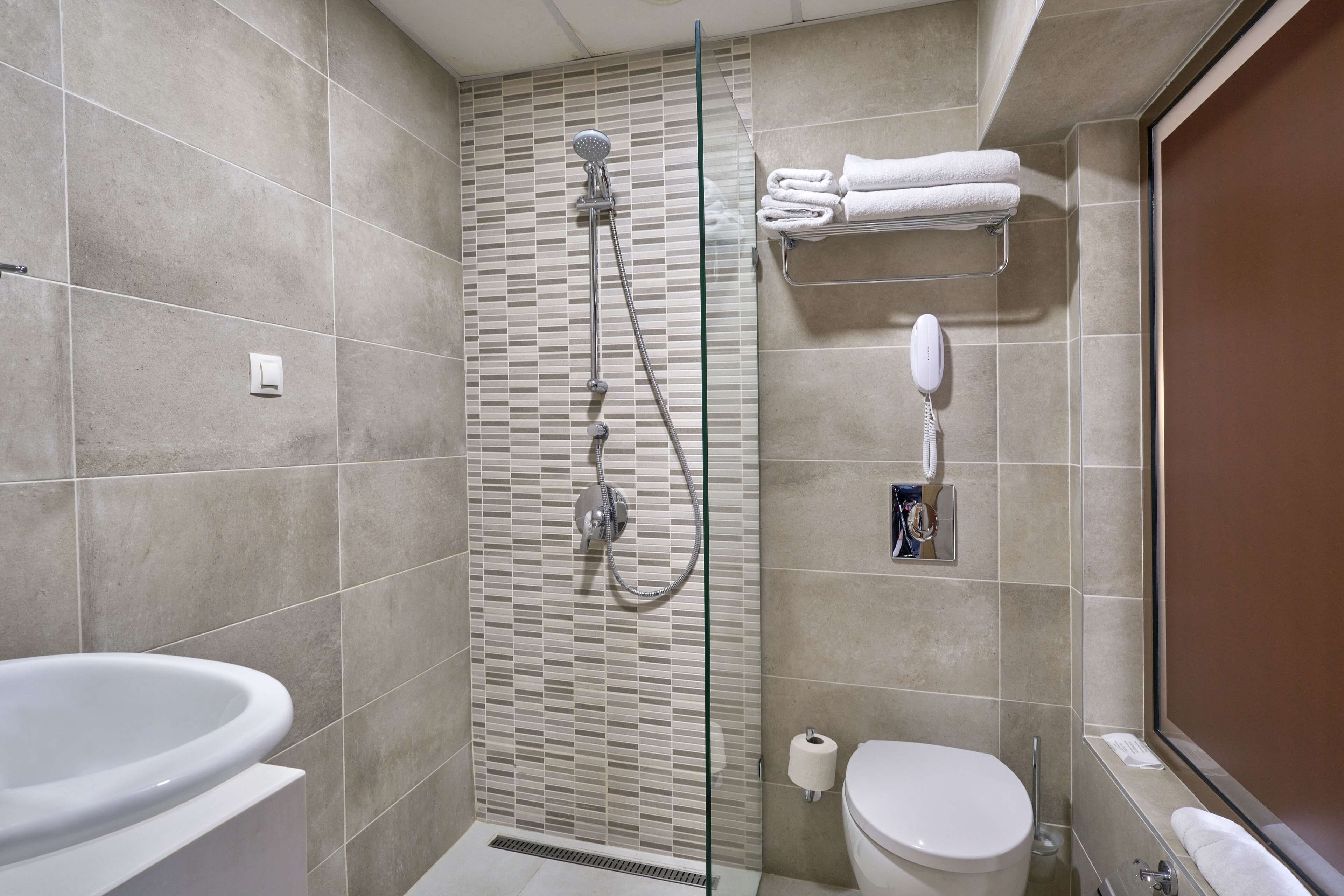 A modern bathroom with a glass-enclosed shower, a toilet, and a bathtub.
