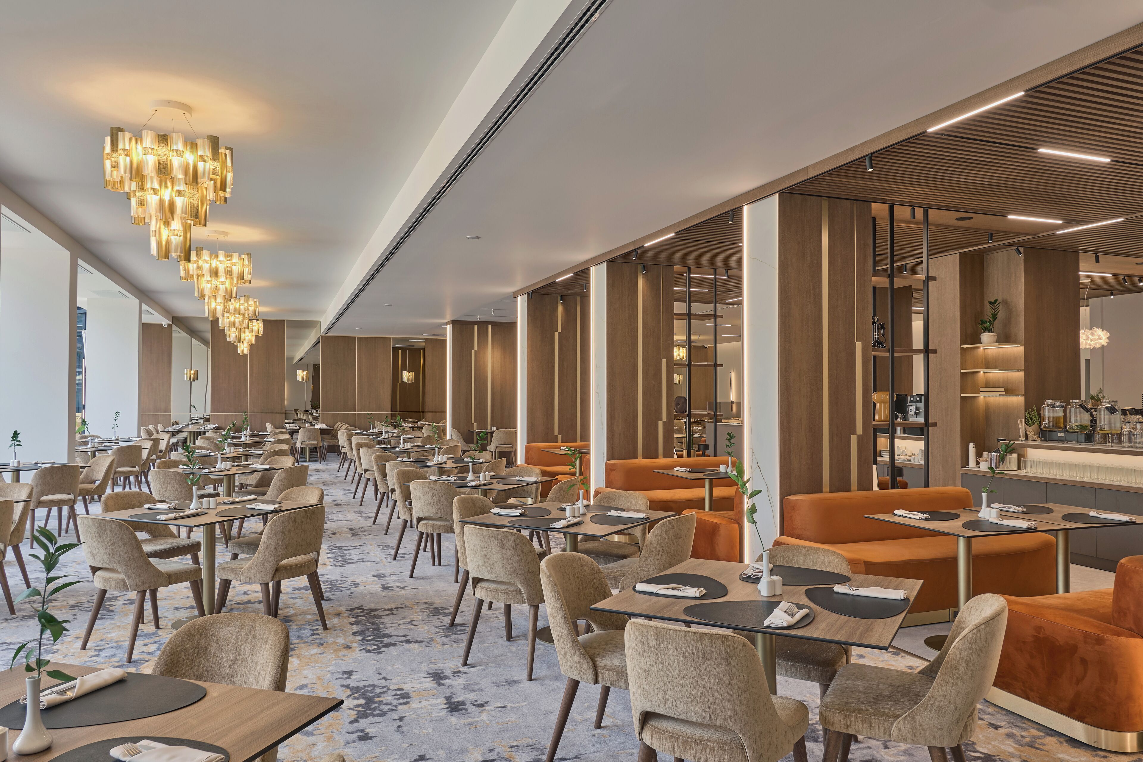 A modern dining area with multiple tables and chairs, a central bar area, and a decorative light fixture.