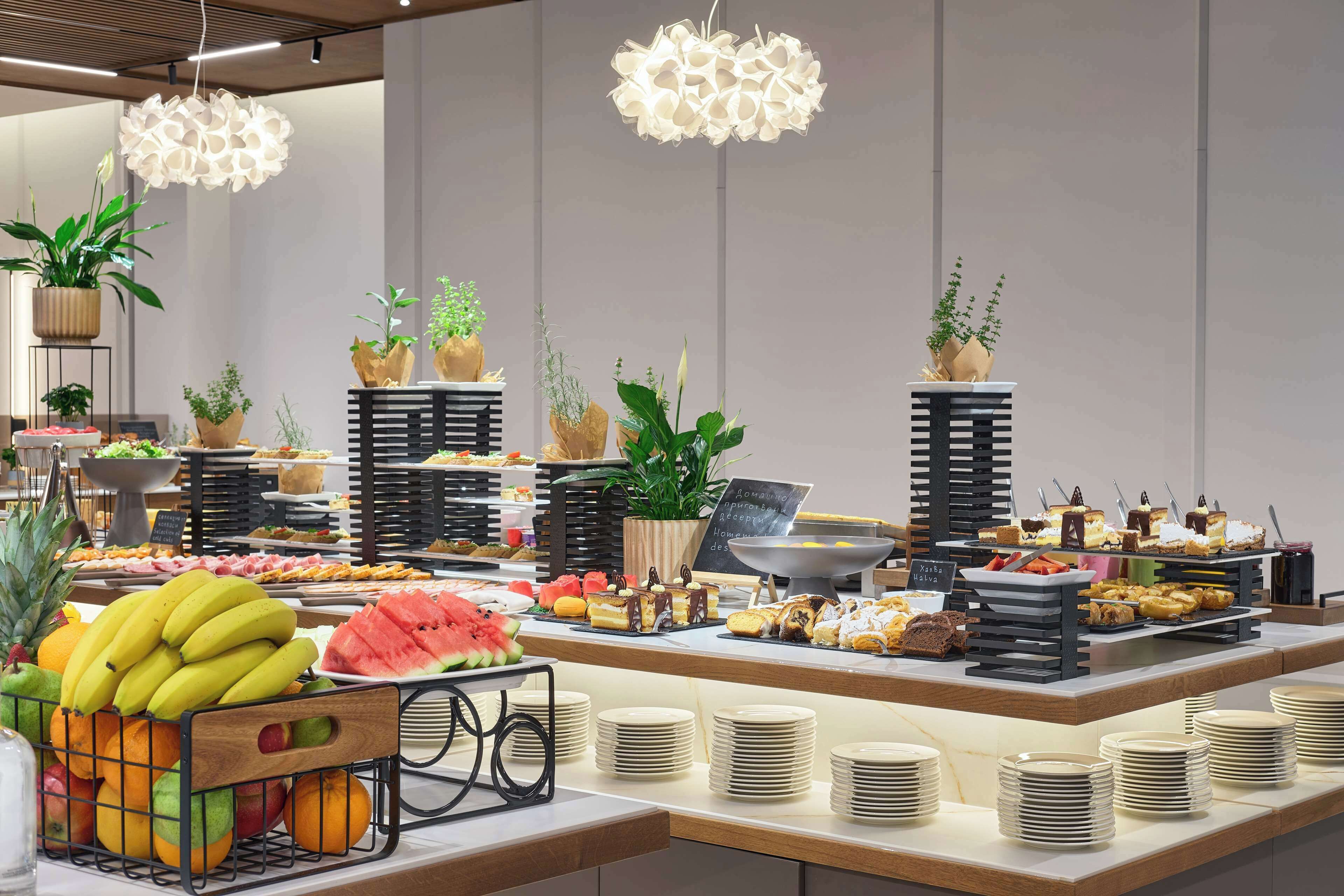 A buffet area with various food items, plates, and decorative plants.
