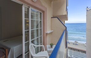 Enjoy the serene beach view from your balcony, complete with a comfortable chair and a potted plant.