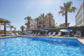 Relax by the pool surrounded by palm trees and lounge chairs.