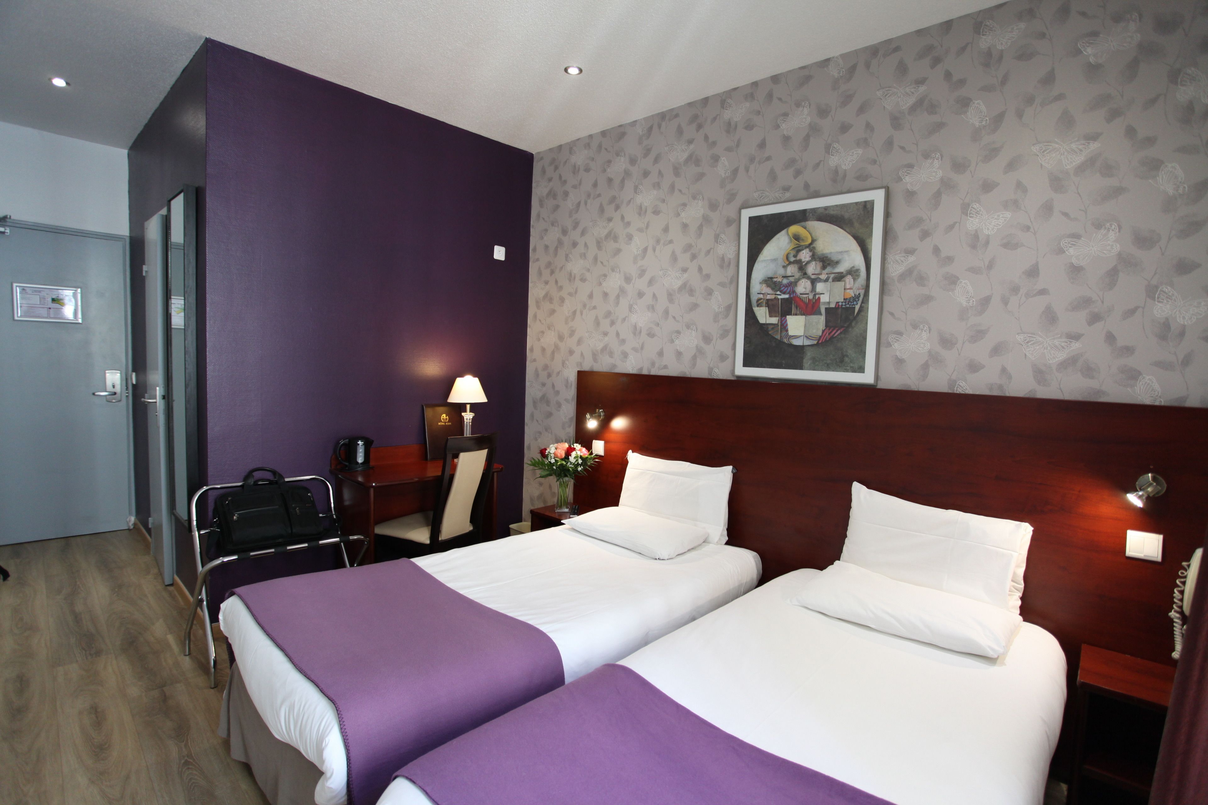 Habitación de hotel con dos camas, un escritorio, una silla y zona de ducha.