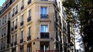 A multi-story building with a classic architectural style, featuring balconies and a sign for "Le Parisien." - Hotel Alane (Paris)