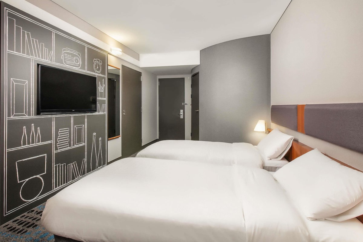 Une chambre d’hôtel avec un grand lit, un téléviseur à écran plat, une armoire et une porte de salle de bain.