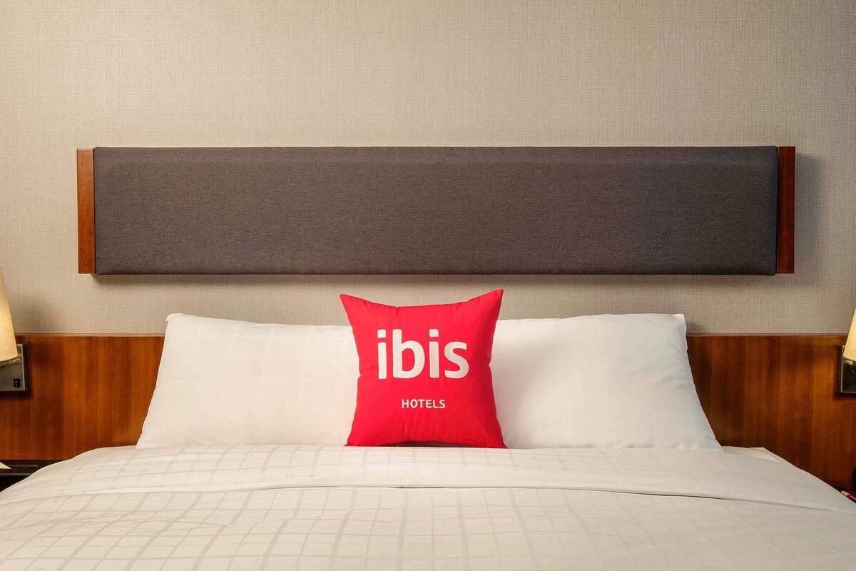 Ein Hotelzimmer mit einem Bett, einem Kopfteil und zwei Nachttischlampen.