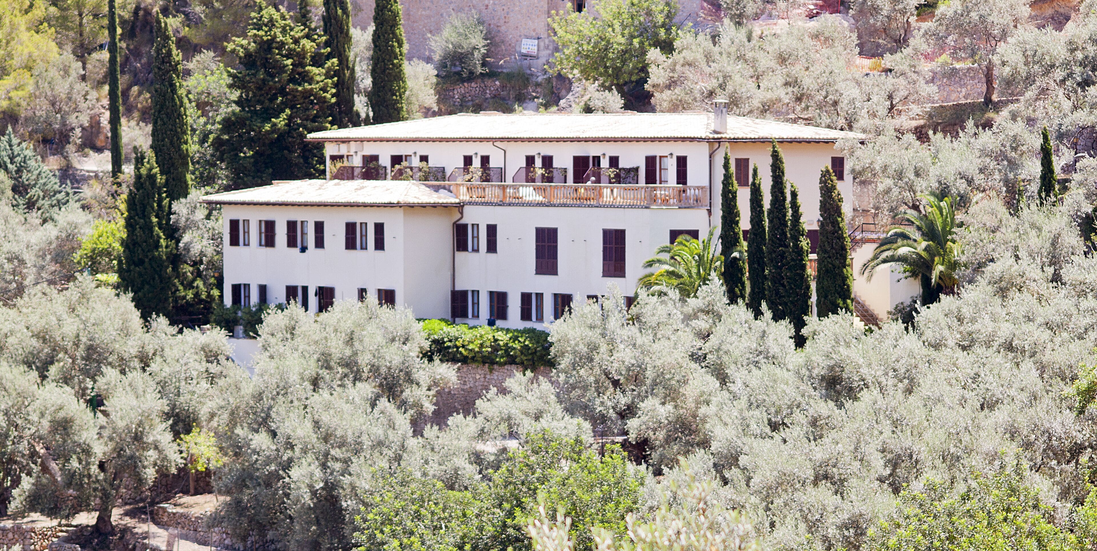 Un bâtiment à deux étages, entouré d’une végétation luxuriante, avec un balcon à l’étage supérieur.