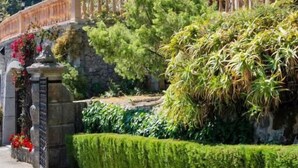 A multi-story building with balconies, surrounded by lush greenery and a stone wall. - Es Moli Hotel (Deià)