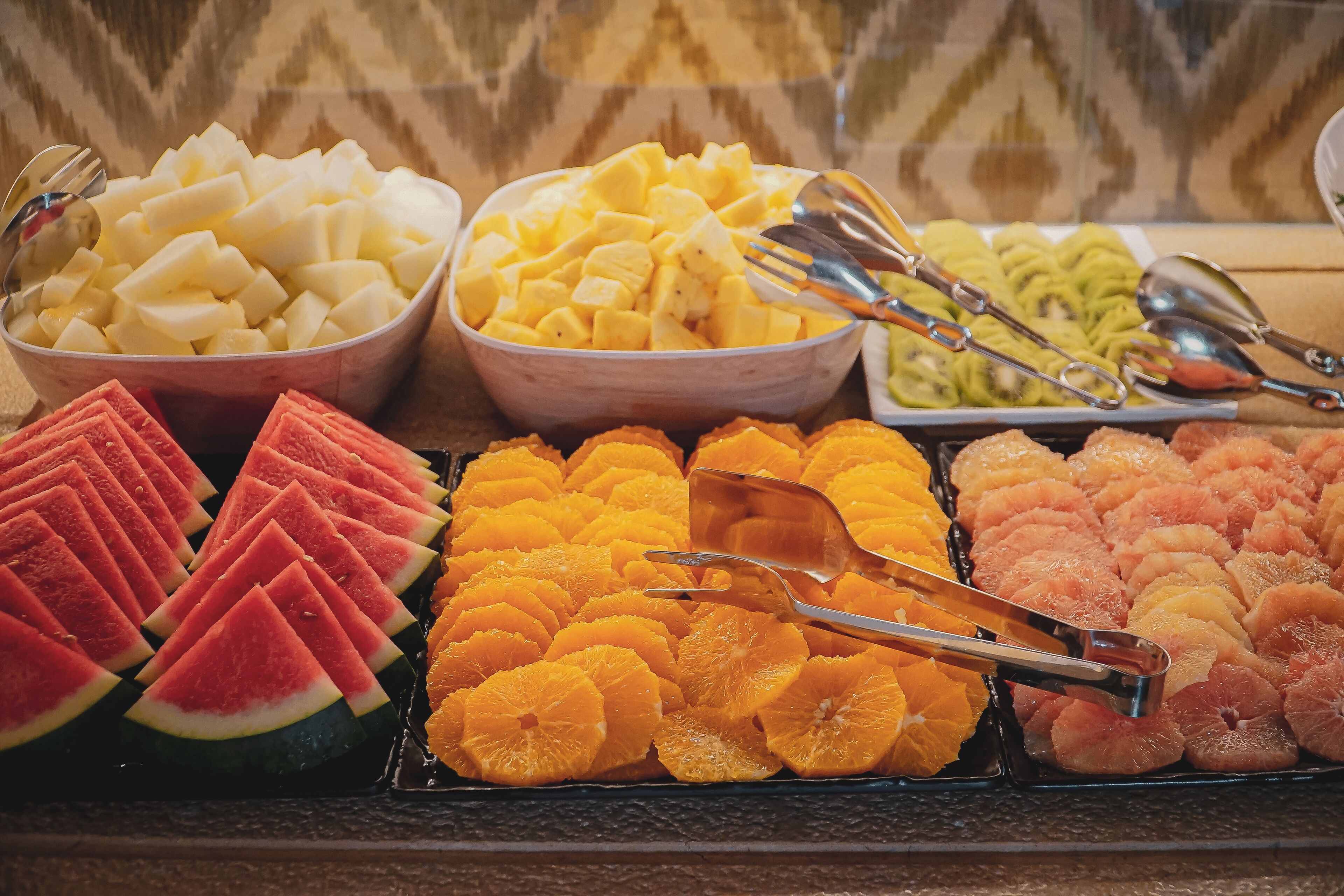 A fruit display with various types of fruits including watermelon, oranges, and kiwi.