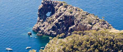 A rocky coastal landscape with clear blue waters and boats.