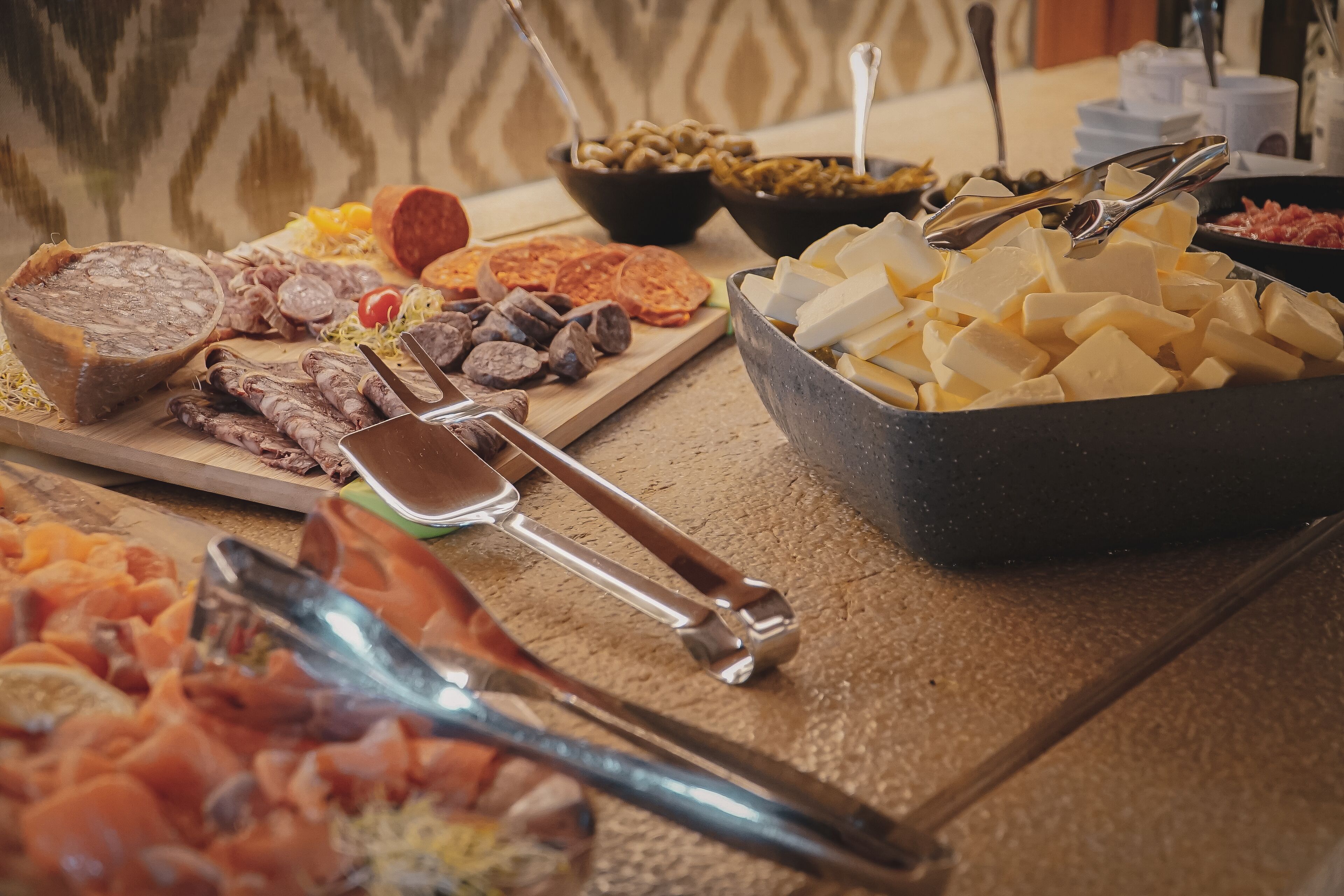 A buffet with various meats, cheeses, and vegetables.