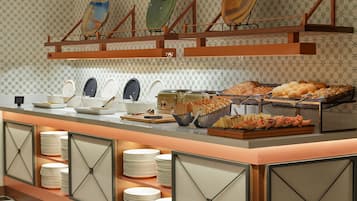A buffet setup with various food items and plates.